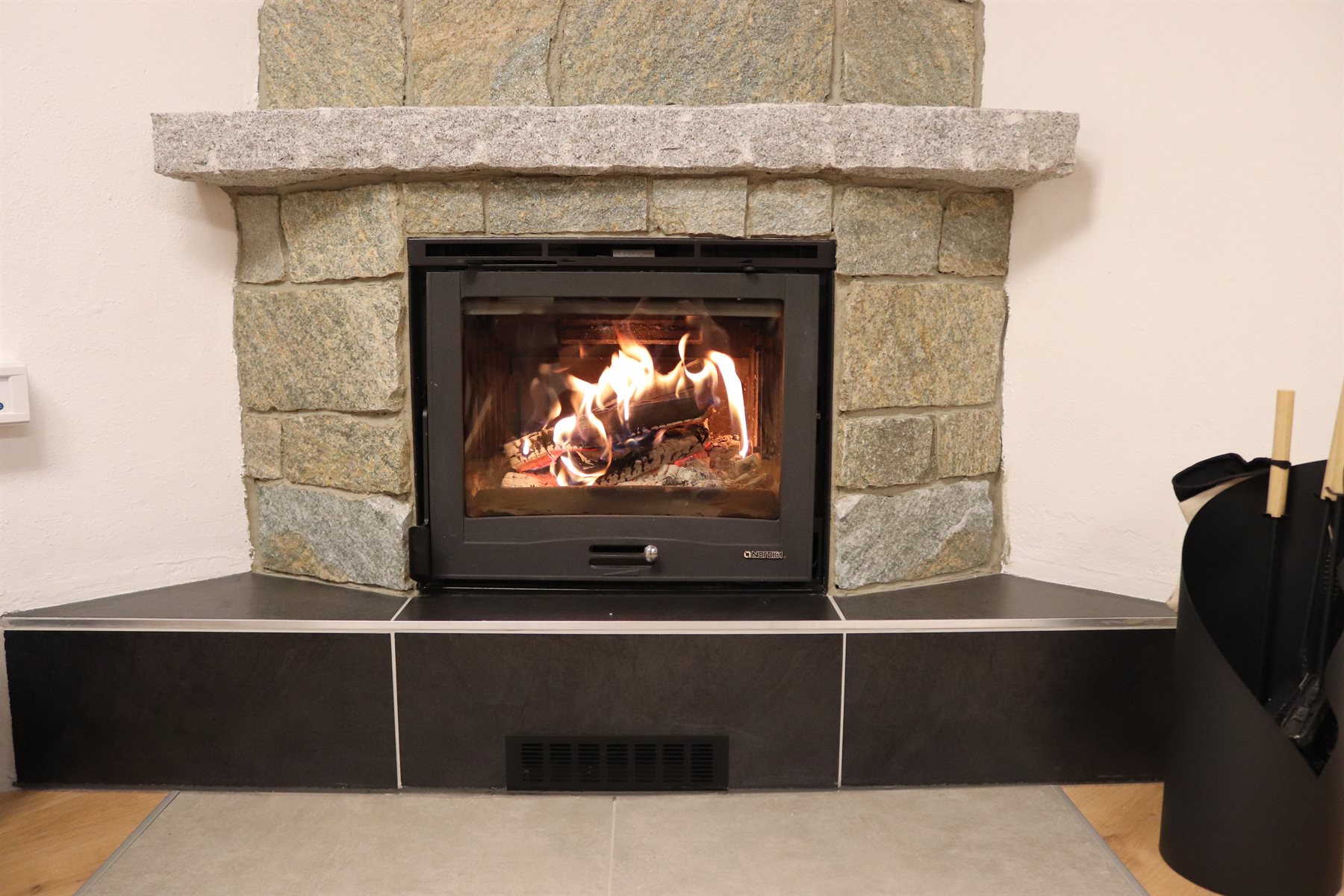 Kamin im Casa di Monti mit brennendem Feuer.